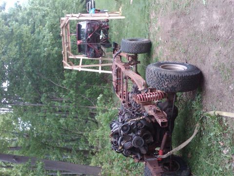 1992 Ford F-150 - The chassis of a truck, including the engine and cab, is suspended by a wooden frame in an outdoor setting.