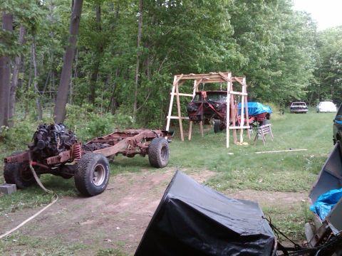1992 Ford F-150 - A disassembled truck chassis sits in a yard with a truck body suspended above the ground.