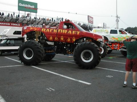 1994 Ford Bronco - A monster truck event with multiple custom trucks on display and spectators in the background.