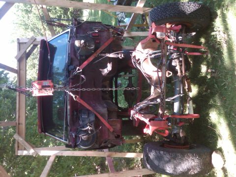 1992 Ford F-150 - The vehicle's chassis and suspension are exposed as it is suspended for repair or modification.