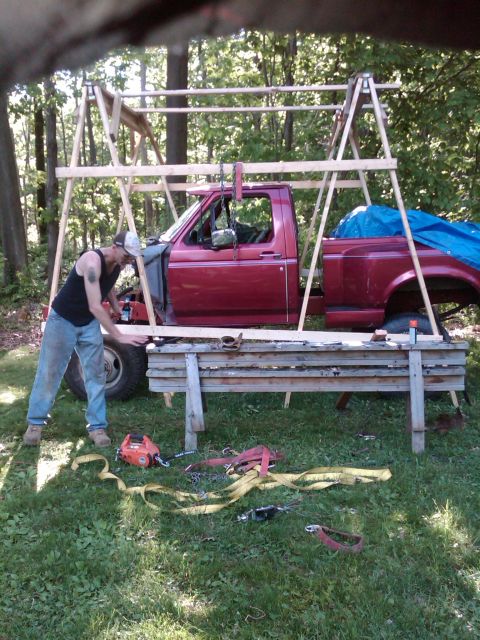 1992 Ford F-150 - A man works on a red 1992 Ford F-150 pickup truck cab and bed supported by sawhorses outdoors.