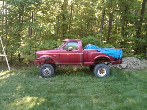 1992 Ford F-150 - Side view of a red 1992 Ford F-150 pickup truck with a blue tarp in the bed.