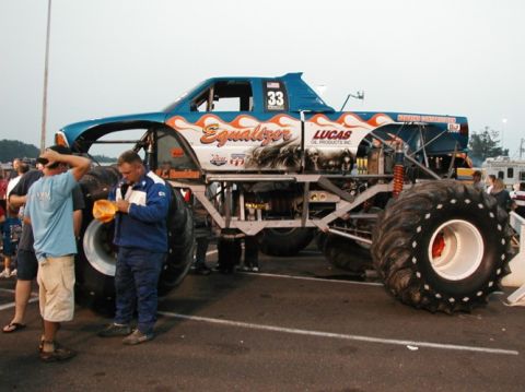 1994 Ford Bronco - A monster truck named "Equalizer" with flame graphics and the number 33 is displayed at an event.