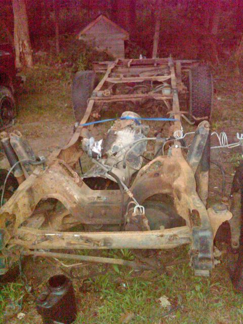 1992 Ford F-150 - The chassis of a heavily rusted truck, with its engine and suspension components exposed, sits in an outdoor setting.