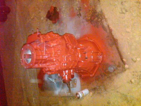 1992 Ford F-150 - A transmission is being painted red, with a spray can visible on the ground.