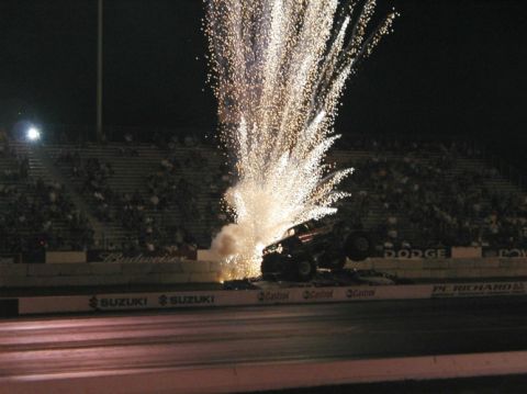 1994 Ford Bronco - A monster truck performs a stunt with pyrotechnics during a nighttime event at a stadium.