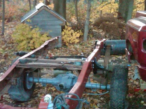 1992 Ford F-150 - Close-up of a truck's frame and rear axle, with a small shed in the background.