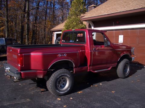 1996 Ford Bronco - This red 1996 Ford F-150 pickup truck is parked in front of a garage.