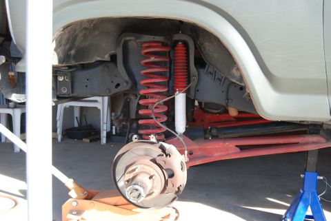 1982 Ford Bronco - Front suspension components, including red coil springs and white shock absorbers, are visible on a vehicle undergoing maintenance.