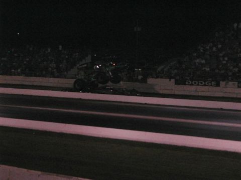 1994 Ford Bronco - Monster truck performs a jump over debris during an event at night.