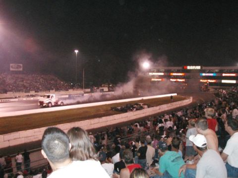 1994 Ford Bronco - A truck performs a burnout during a drag race event at night, with a large crowd watching from the stands.