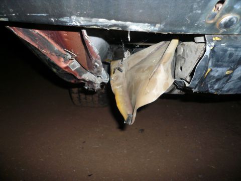 1975 Ford Ranchero - Close-up view of the damaged rear bumper and undercarriage of a vehicle, showing bent metal and debris.