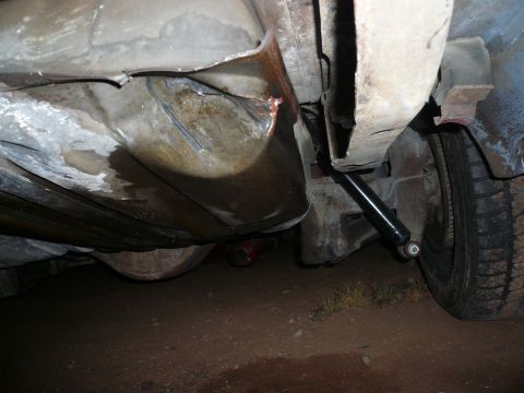 1975 Ford Ranchero - Undercarriage view of a vehicle, focusing on a damaged fuel tank and suspension components.