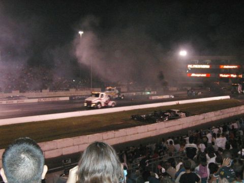 1994 Ford Bronco - Drag racing event at night with two trucks competing on the strip.