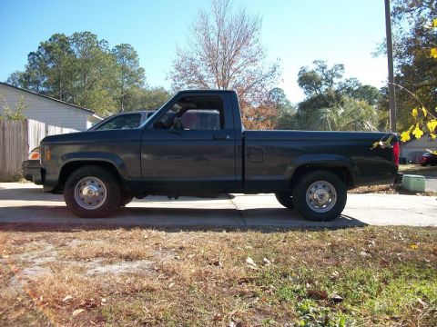1987 Ford Ranger - This pickup truck is parked on a paved surface with a house and trees in the background.
