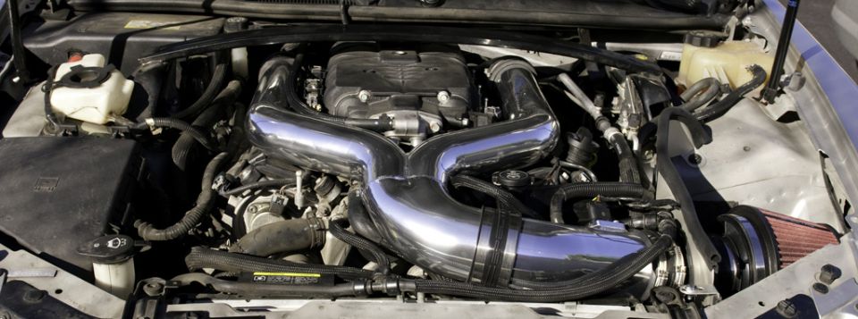 2006 Cadillac STS engine bay with chrome intake tubes and red air filter