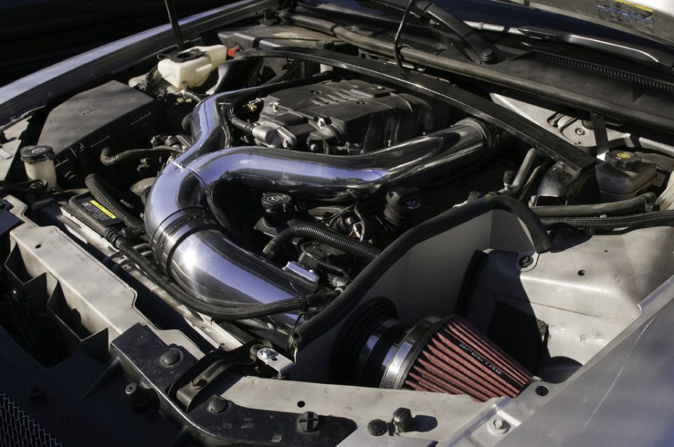 Engine bay with chrome intake tube and red air filter. Supermotors.net logo visible