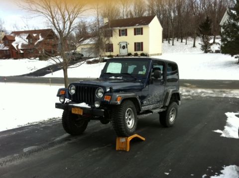 1972 Ford Ranchero - Dark blue Jeep Wrangler TJ with a hardtop flexing its suspension in a snowy driveway, driver-side front wheel climbing a yellow ramp so the…