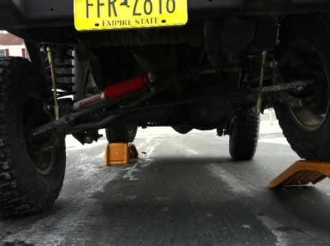 1972 Ford Ranchero - The underside of a lifted vehicle is shown, large tires and a yellow New York license plate.