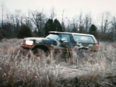 1995 Ford Bronco - A 1995 Ford Bronco navigates through tall grass and mud.