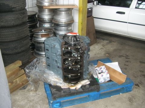 1972 Ford Ranchero - Engine block on a pallet, with tires and rims stacked nearby. A white car is visible in the background.