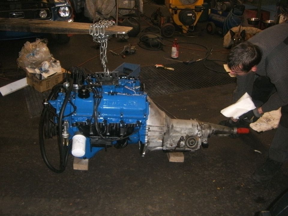 Blue engine and transmission assembly on wooden blocks in a garage