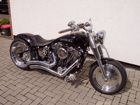 1972 Ford Ranchero - A custom motorcycle with a black finish and numerous chrome details is parked outside against a white wall.