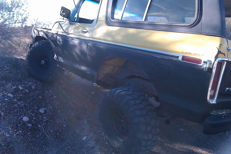 Side rear of a lifted two-tone SUV on off-road terrain