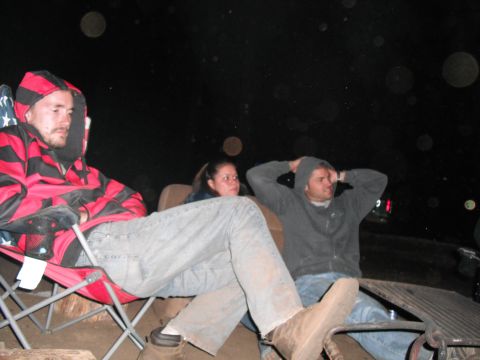 1991 Ford Bronco - Three people are seated in chairs outdoors at night, with one person in the foreground wearing a red and black striped hooded jacket.