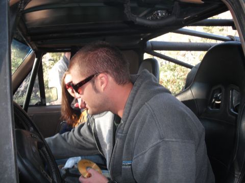 1991 Ford Bronco - Two people are inside a vehicle with a roll cage, looking out at the scenery.