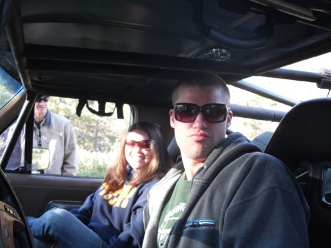 1991 Ford Bronco - Three people are inside a vehicle, two in the front seats and one standing outside the open door.