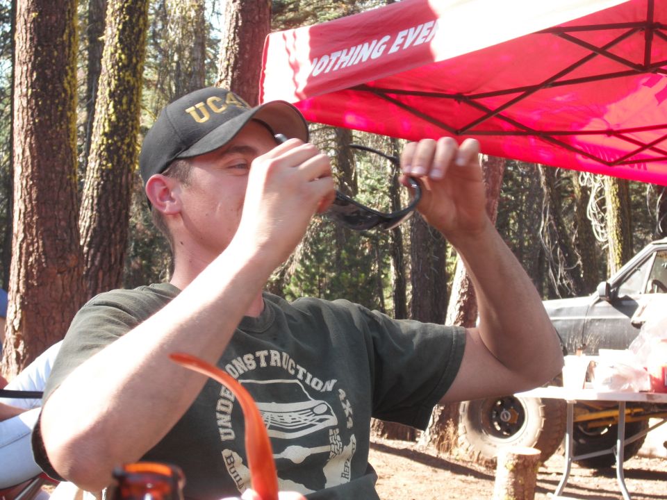 Man cleaning sunglasses at a campsite with a vehicle in the background