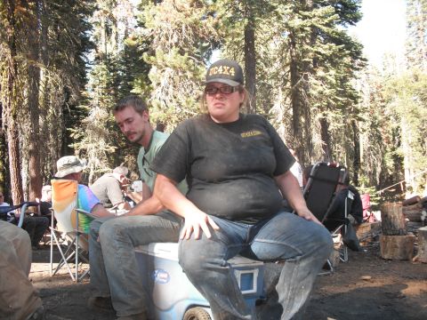 1991 Ford Bronco - A group of people are gathered outdoors in a forest setting, with some seated and others in the background.