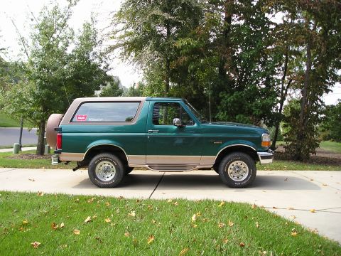 1996 Ford Bronco - Side view of a 1996 Ford Bronco, its distinctive two-tone paint scheme and rear-mounted spare tire.
