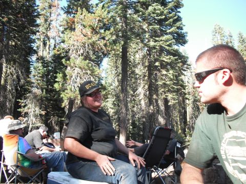 1991 Ford Bronco - A group of people enjoy a camping trip in a wooded area, with one individual sporting a UC Davis baseball cap.