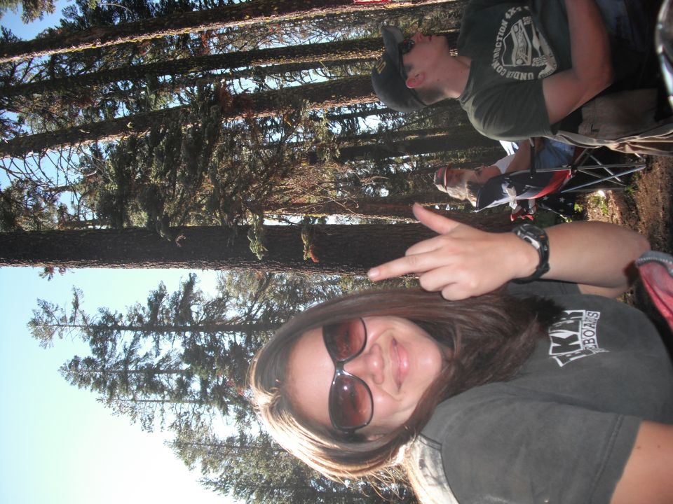 Two people in a forest, one giving the middle finger