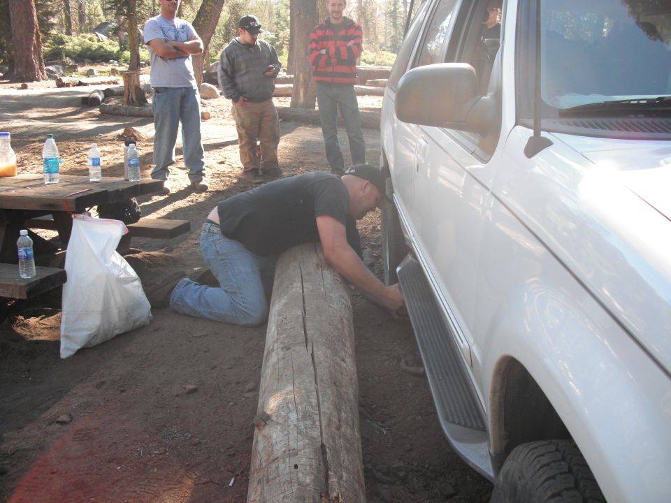 White SUV side view with running boards, man working on wheel