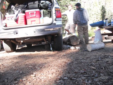 1991 Ford Bronco - A silver Ford Bronco is packed with camping gear, parked at a campsite with two men nearby.