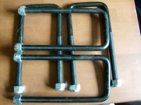 1986 Ford Bronco - Several U-bolts with nuts are laid out on a wooden surface.