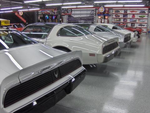 1979 Chevrolet Camaro - Several white Pontiac Firebird Trans Ams are parked in a garage, with a red car in the background.