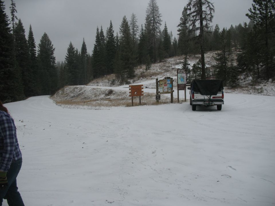 Truck with cargo cover parked on snowy ground near trail signs