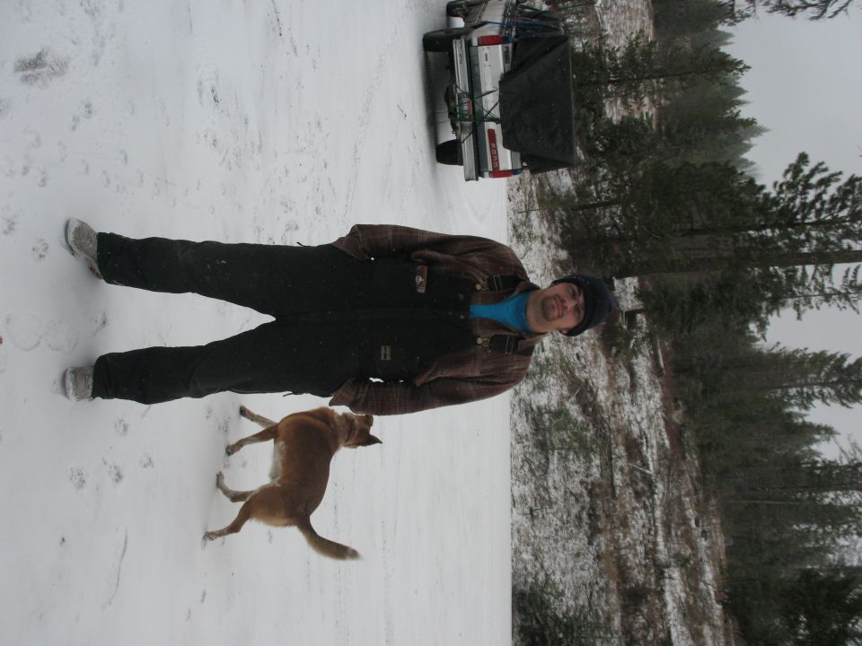 Man and dog in snow next to a 1995 Ford Bronco with a trailer