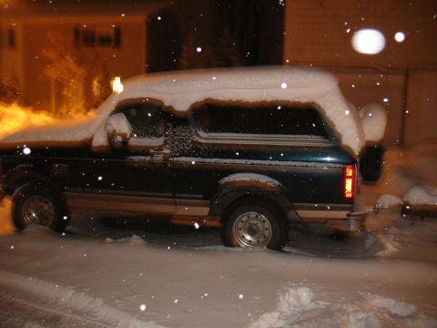 1995 Ford Bronco - A Ford Bronco is parked outside during a snowstorm at night.