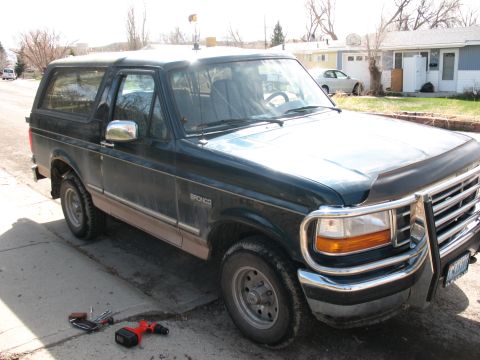 1995 Ford Bronco - 1995 Ford Bronco parked on a street with a bull bar and tools nearby.