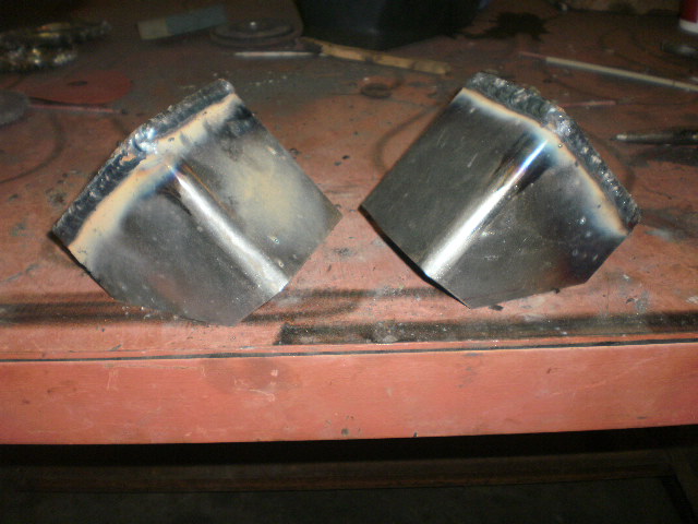 Two welded metal brackets on a workbench