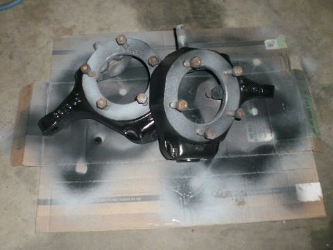 1995 Ford Bronco - Two black painted steering knuckles are shown, likely for a vehicle's suspension system.