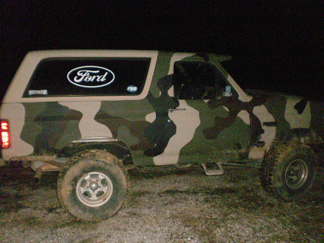 Side view of a Ford Bronco with a camouflage wrap. It has a Ford logo on the rear window
