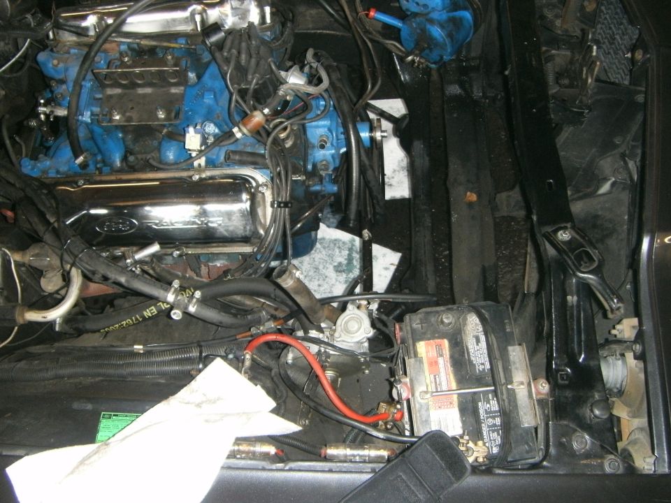 Engine bay with blue engine block, chrome valve covers, and battery