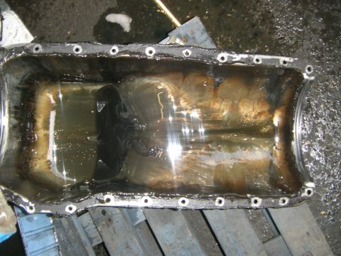 1972 Ford Ranchero - An oil pan, likely removed from an engine, shows signs of wear and residue.