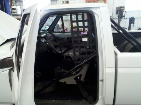 1994 Ford F-150 - The interior of a white pickup truck is shown with a roll cage and racing net installed.